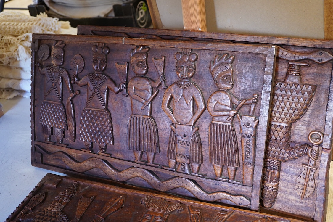 A set of three African carved figurative wooden panels, 64.5cm wide x 37cm high